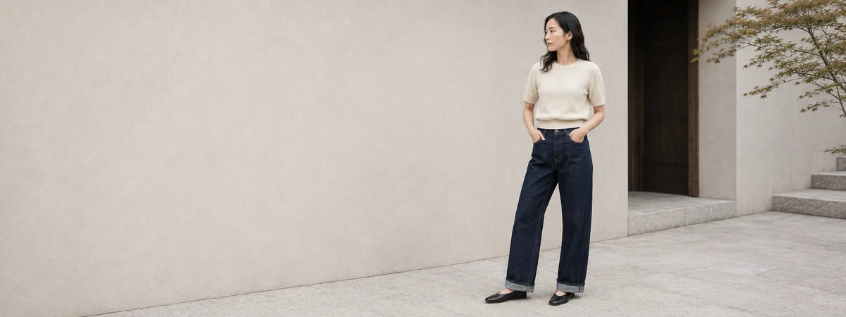Femme portant un jean japonais ample à taille haute en denim indigo devant une architecture minimaliste.