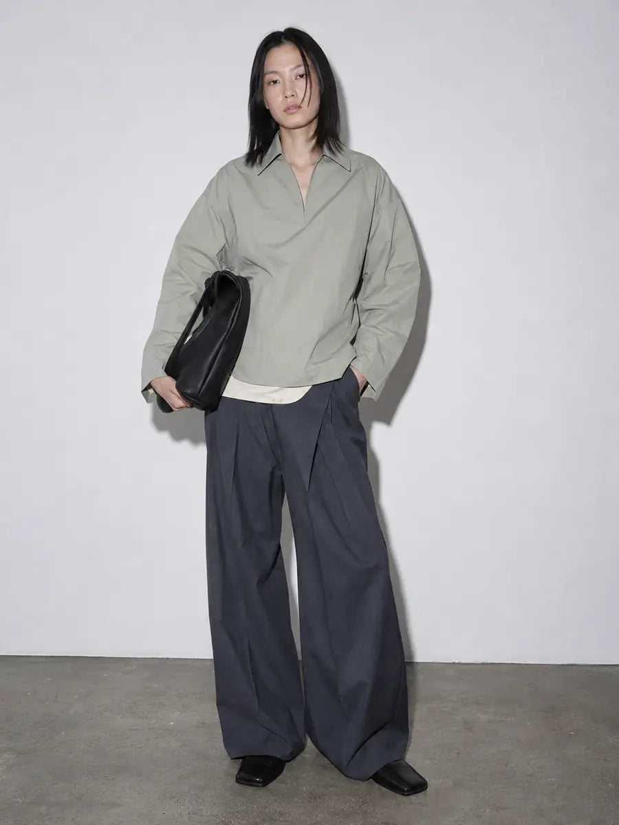 Femme asiatique portant une chemise oversize vert sauge, un pantalon large anthracite et un sac noir